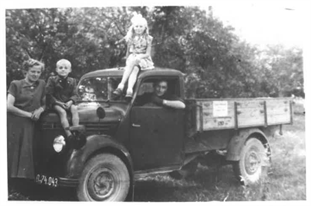 Ein altes schwarzweiß Foto von einem Lieferwagen mit der Familie Wildberger.
